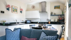 A compact living space with a kitchenette, a sofa with patterned cushions, a dining area, and a small kitchen counter. - Deluxe 2 bedroom upper floor apartment (Harrogate)