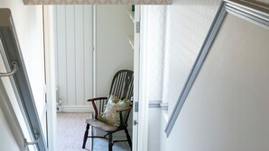 A staircase leading to a room with a patterned curtain, a wooden chair, and a carpeted floor. - Deluxe 2 bedroom upper floor apartment (Harrogate)