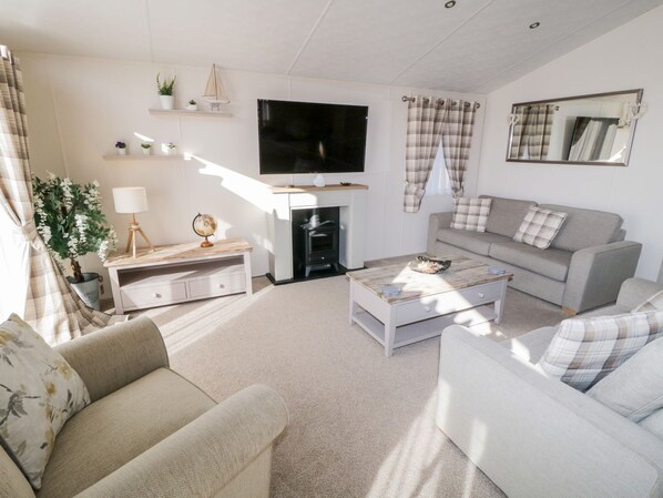 A modern living room with a flat-screen TV, a fireplace, a sofa, and a coffee table.