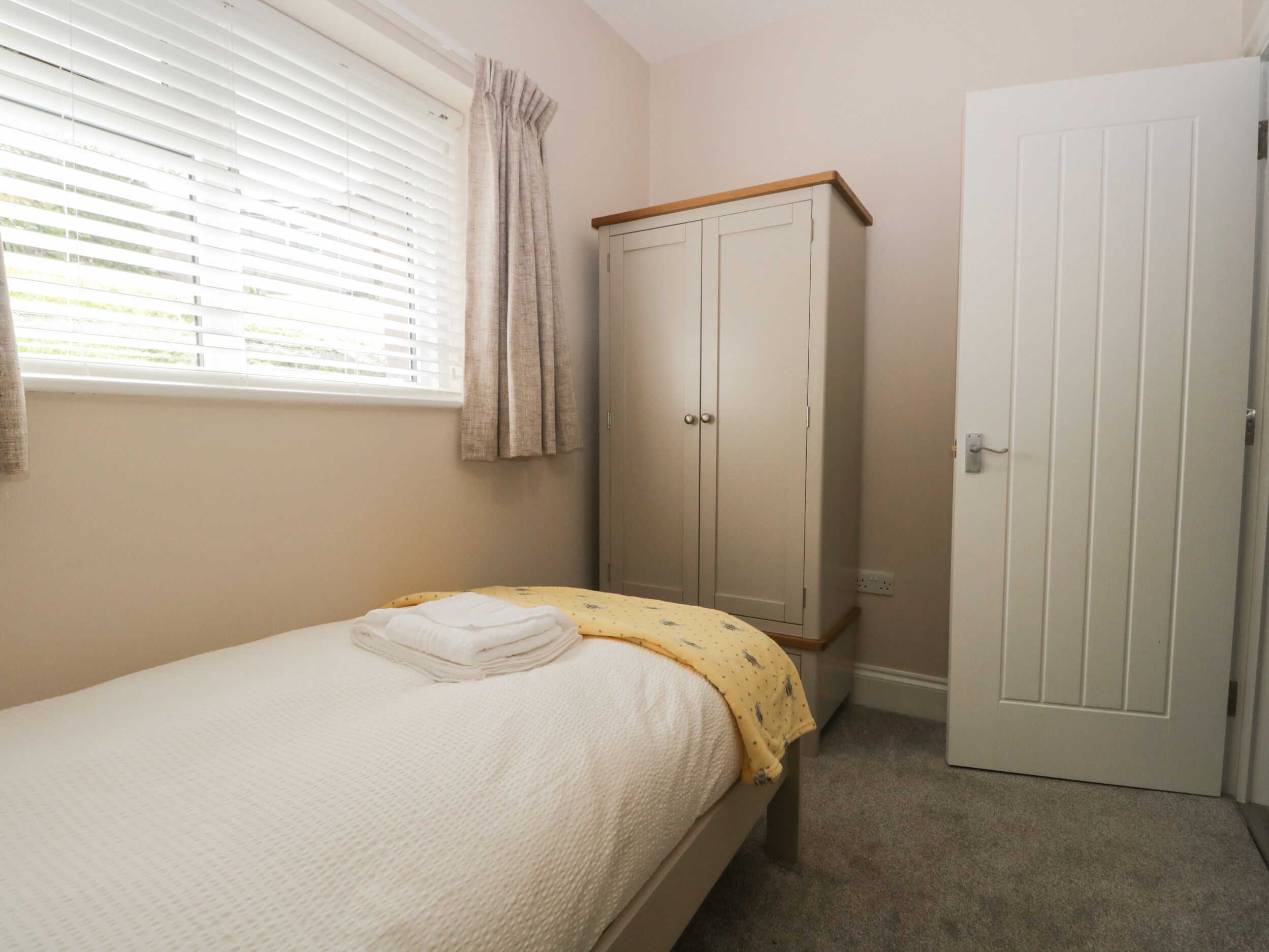 Un dormitorio con una cama individual, un armario y una puerta.