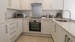 Una cocina moderna con armarios blancos, horno empotrado, microondas y un lavabo.