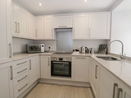 A modern kitchen with white cabinets, a built-in oven, a microwave, and a sink.