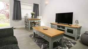 Una sala de estar moderna con televisión, sofá y comedor.