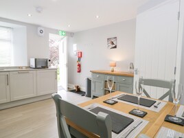 A modern kitchen with white cabinets, a microwave, and a dining area with a wooden table set for two.