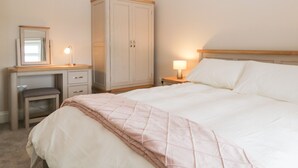 A bedroom with a bed, a desk, a chair, a wardrobe, and a nightstand with a lamp. - Oxen Park Farm Cottage (Ulverston)