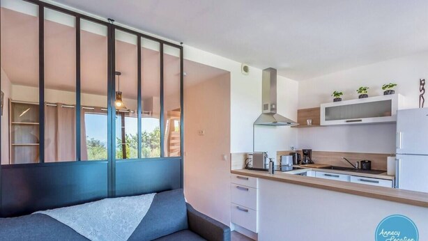 Una cocina moderna con una isla integrada, armarios blancos y vistas a través de un ventanal amplio.