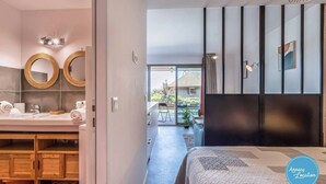 Un dormitorio moderno con una cama grande, un armario de madera y un baño con dos espejos redondos y un lavabo.