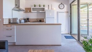 Cozinha moderna com ilha central, eletrodomésticos embutidos e uma janela ampla que ilumina naturalmente o espaço.