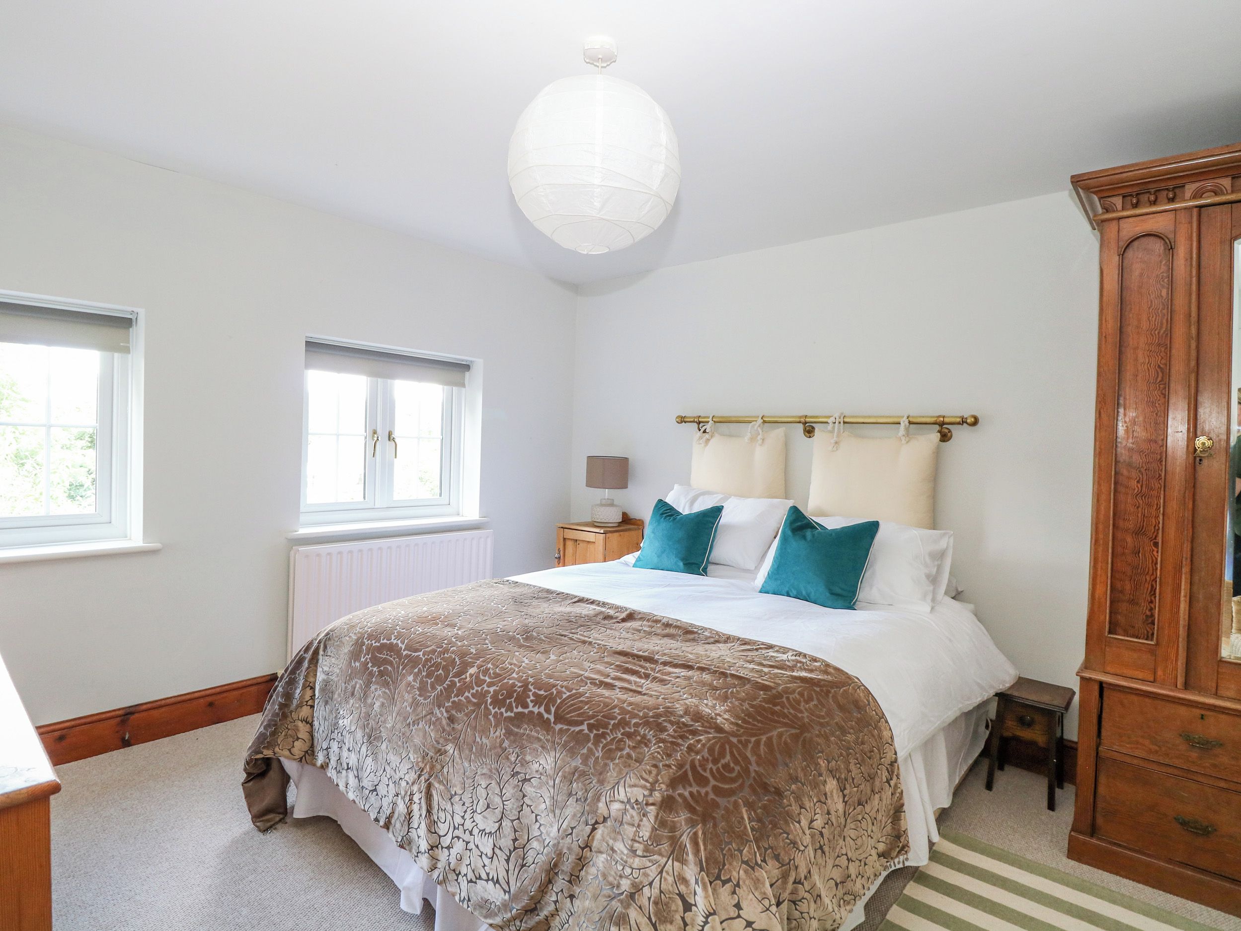 Un dormitorio con una cama, un armario de madera, una ventana y un radiador.