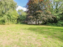 A grassy field with trees and a building in the background.