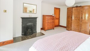 A bedroom with a fireplace, wooden wardrobe, and a mirror on the wall.