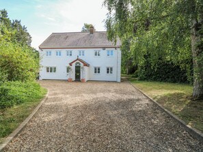 Uma casa branca de dois andares com um caminho de cascalho e um pequeno jardim.