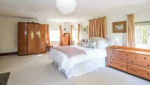 A spacious bedroom with a large bed, wooden wardrobe, and a hanging light fixture.
