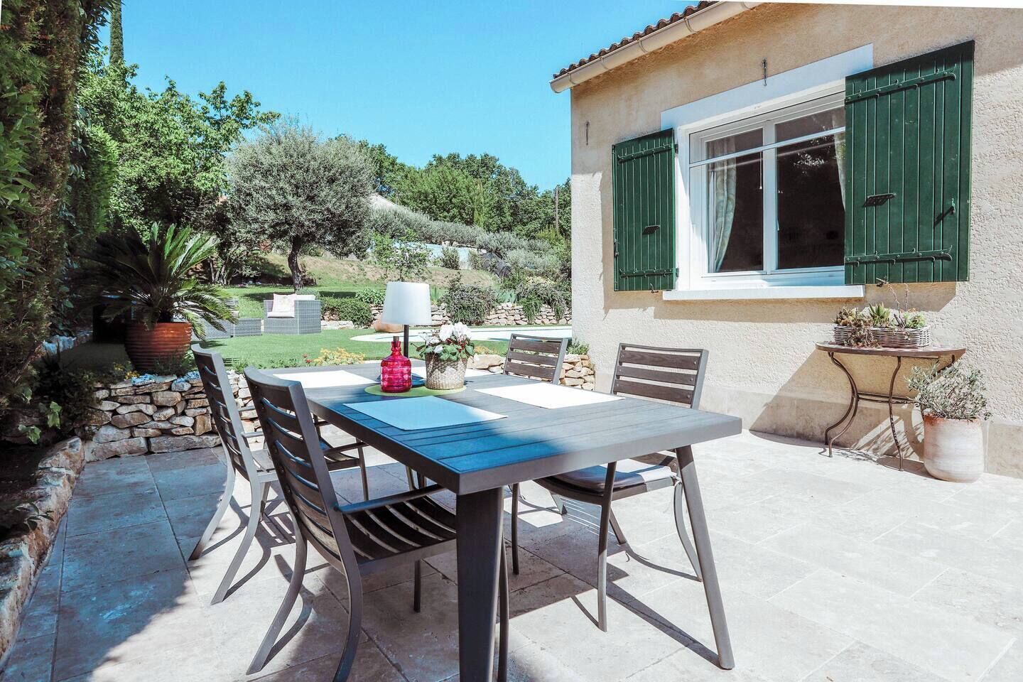 An outdoor patio with a table and chairs, a lamp, and potted plants.