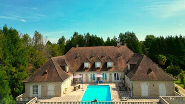 A large house with a swimming pool, surrounded by trees and a clear sky. - Le Belvedere (Thiviers)