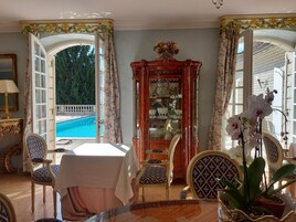 Habitación con vista a la piscina, muebles ornamentados y una vitrina de cristal.