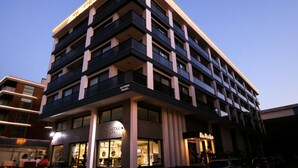 A multi-story hotel with a modern design, featuring balconies on each floor and a prominent entrance with signage. - Krem Marin Suites (Cesme)
