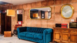 Une pièce avec un canapé en velours bleu, un meuble en bois et un mur en briques.