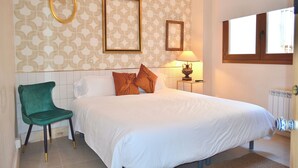 Une chambre à coucher avec un lit, une chaise, une lampe et une fenêtre.