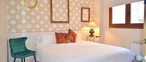 A bedroom with a bed, a chair, a lamp, and a window.