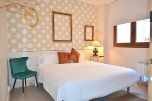 Un dormitorio con cama, una silla, una lámpara y un ventanal.