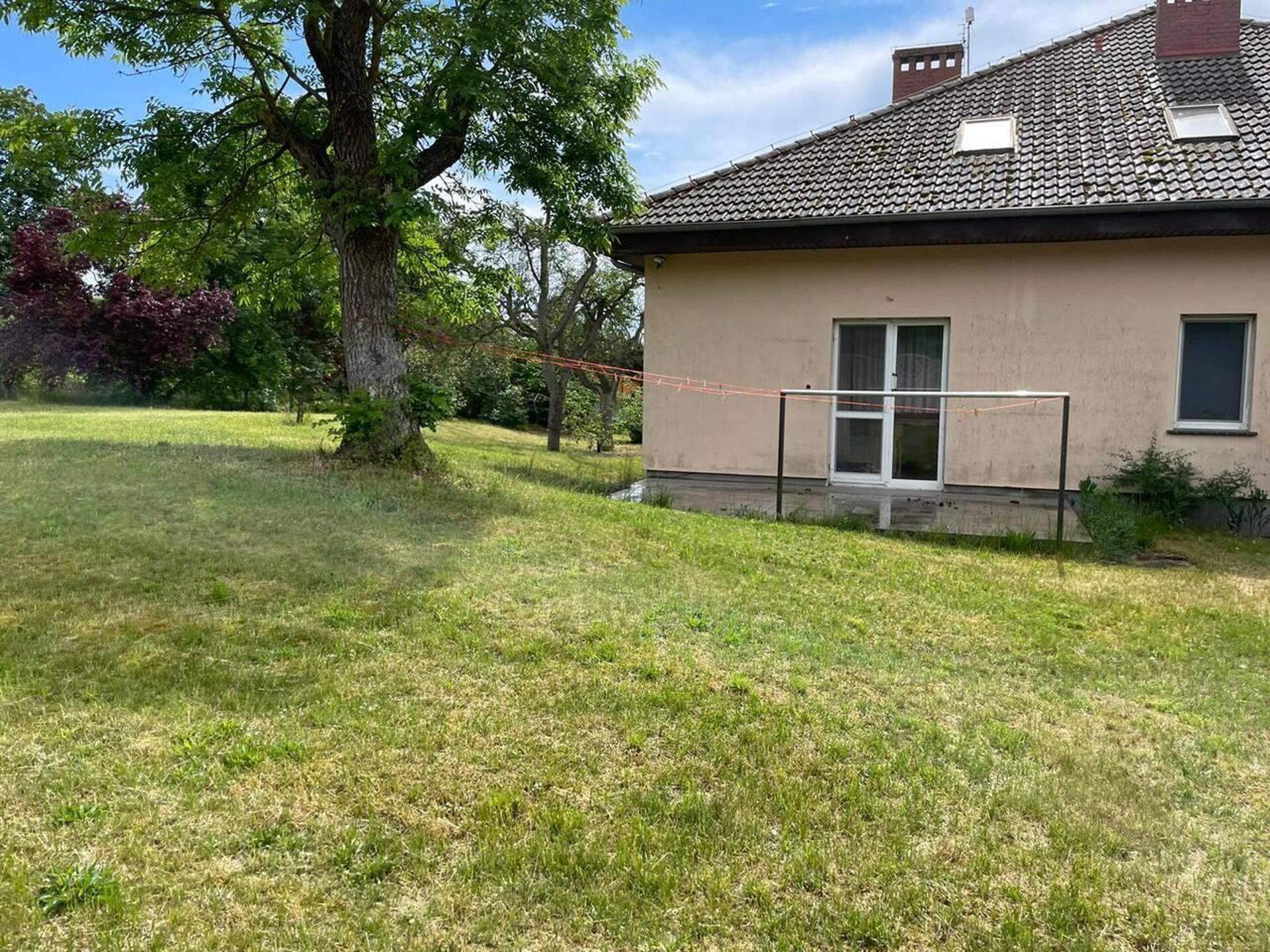A house with a tiled roof, a small porch with a glass door, and a grassy yard.