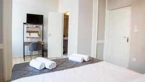 A hotel room with a bed, a desk, a chair, and a television. - One Three One (Athens)