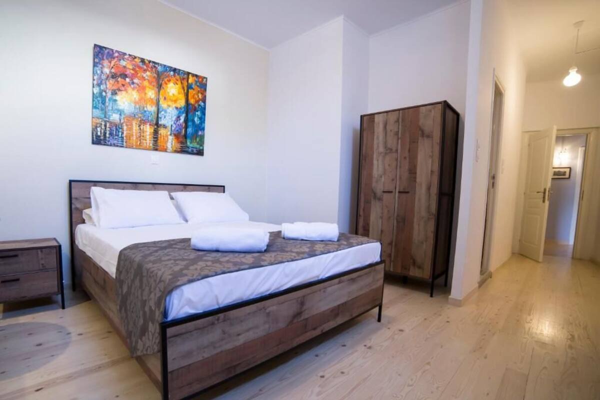 Ein Schlafzimmer mit einem hölzernen Bett, einem Kleiderschrank und einem Gemälde an der Wand.