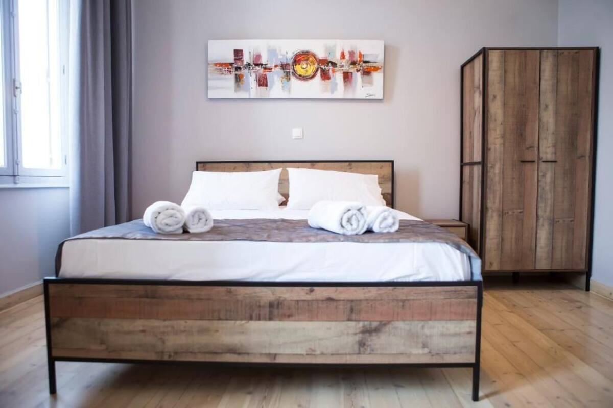 Ein Schlafzimmer mit einem hölzernen Bett, weißer Bettwäsche und einem großen Kunstwerk an der Wand.