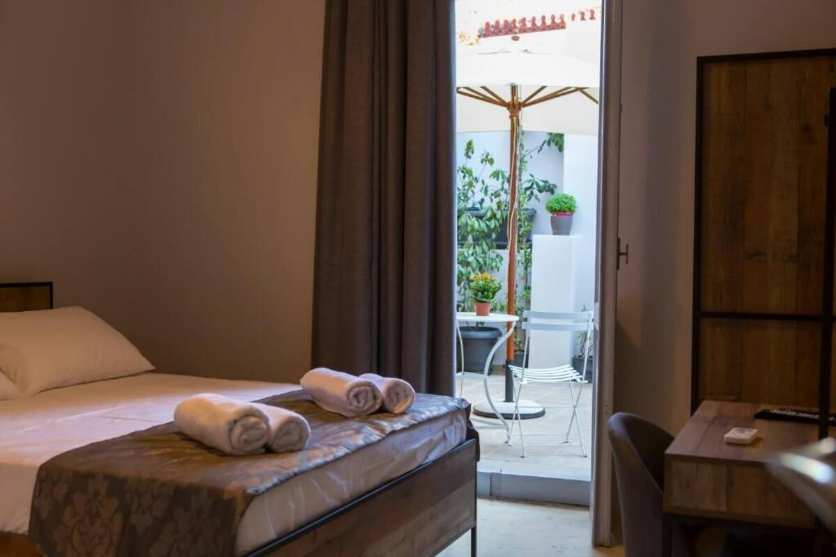 Ein Hotelzimmer mit Bett, Schreibtisch und Blick auf den Außenbereich inklusive Tisch und Stühlen.