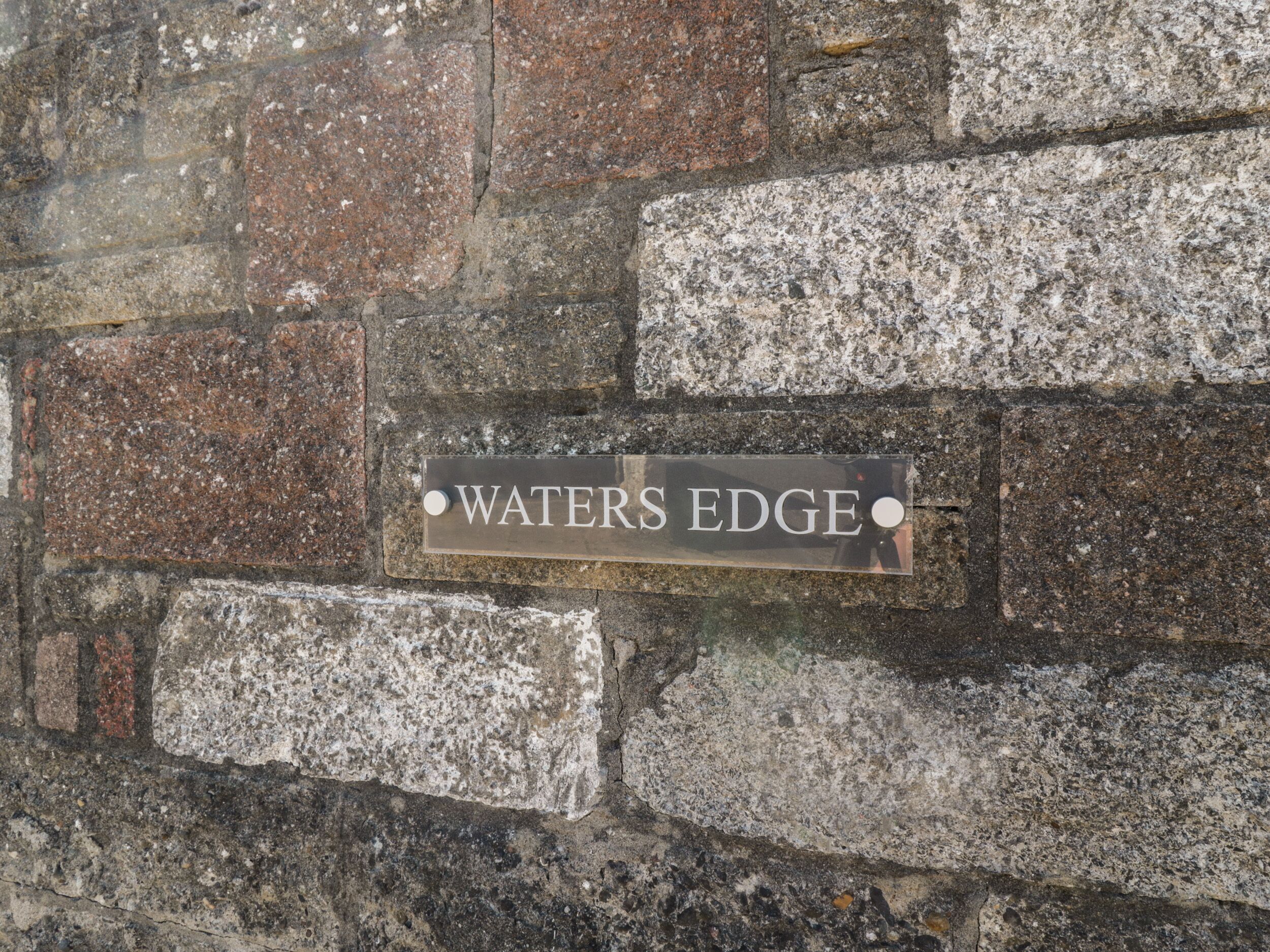 Et skilt på en stenvæg med teksten 'WATERS EDGE'.