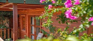 A wooden cabin with a porch, wooden doors, and a small table. - Felicity Hotel & Bungalows (Kemer)