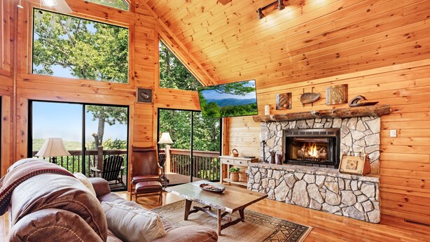 A cozy cabin interior with a stone fireplace, wooden walls, and large windows offering scenic views. - Early Rise - Blue Ridge  (Blue Ridge)