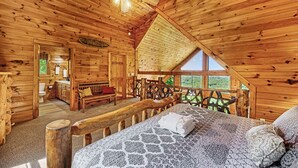 A log cabin bedroom with a bed, a wooden ceiling fan, and a view of the outdoors through a window. - Early Rise - Blue Ridge  (Blue Ridge)