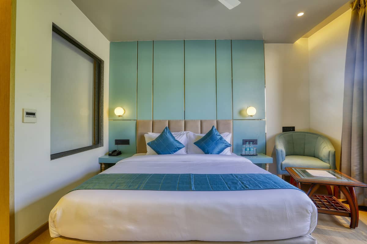 Ein Hotelzimmer mit einem großen Bett, zwei Nachttischen, einem Sessel und einem Schreibtisch.
