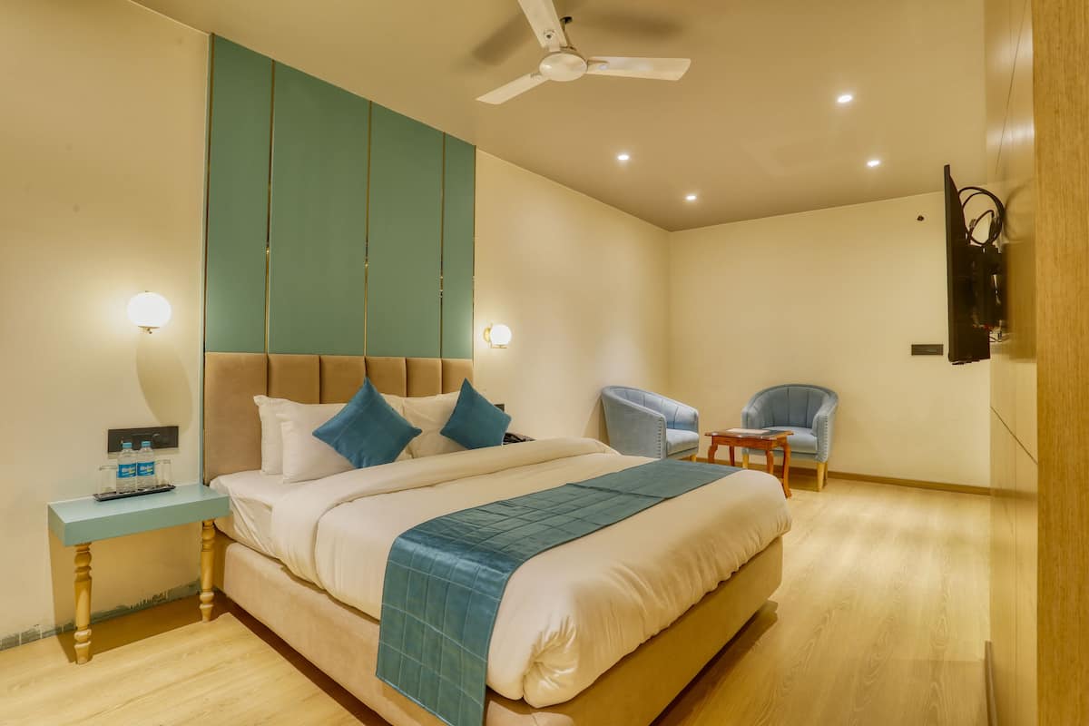Ein Schlafzimmer mit Bett, Nachttisch, Deckenventilator und einem an der Wand montierten Fernseher.