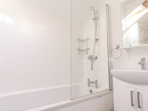 A modern bathroom with a glass-enclosed shower, a white sink, and a mirror above the sink.