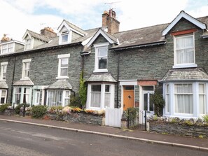 A row of terraced houses with stone facades, white window frames, and pitched roofs.