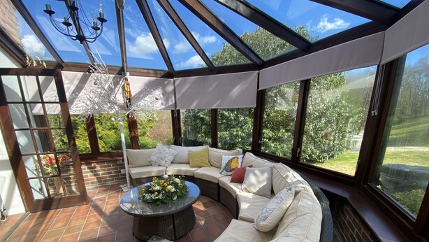 A sunroom with a glass ceiling, a sectional sofa, a round coffee table, and a small side table. - Hidden gem with hot tub  and tennis court in idyllic East Sussex  countryside . (Hellingly /Hailsham)