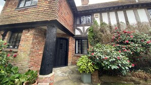 A traditional half-timbered house with a black door, a visible chimney, and a garden with flowering plants. - Hidden gem with hot tub  and tennis court in idyllic East Sussex  countryside . (Hellingly /Hailsham)