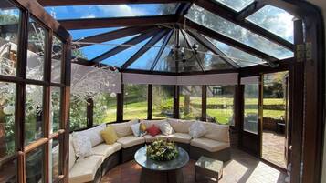 A sunlit room with a glass ceiling, a curved sofa, and a round coffee table.