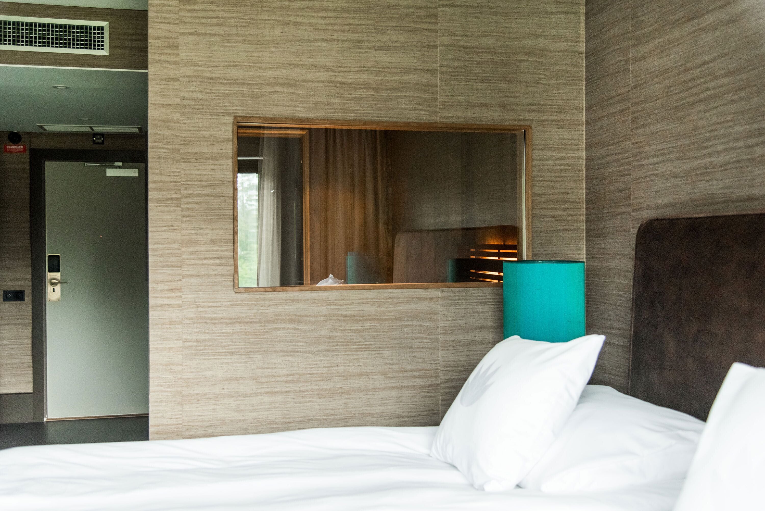 Una habitación de hotel con una cama, un espejo y una puerta.