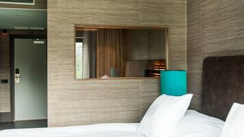 Una habitación de hotel con una cama, un espejo y una puerta.
