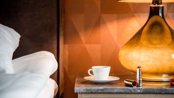 A white cup on a saucer, a lamp, and a lipstick on a wooden table.