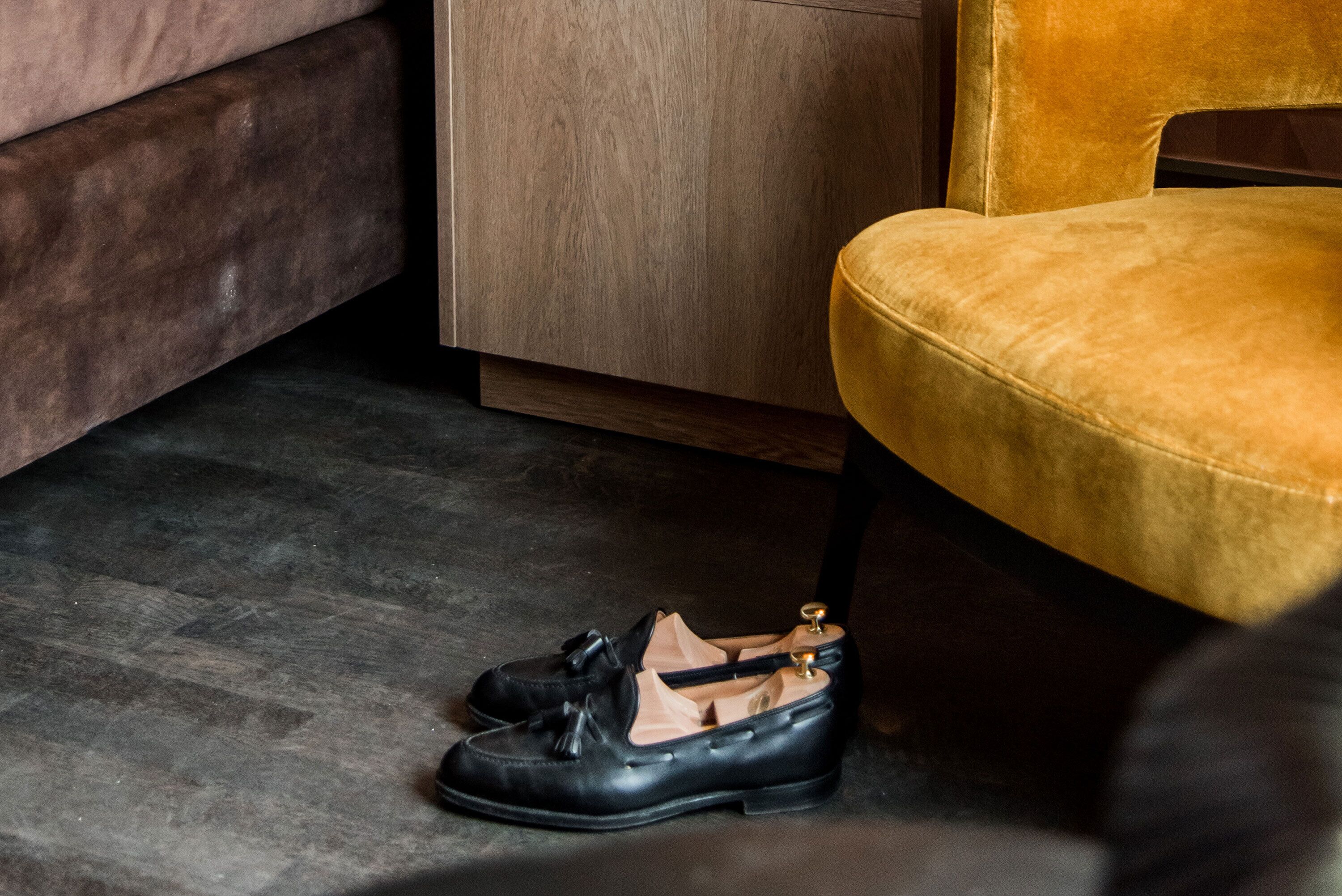 A pair of black shoes with tassels on a dark wooden floor.