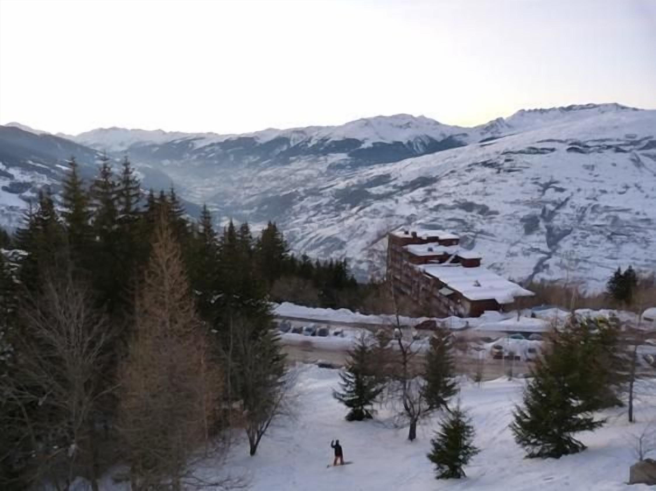 A snow-covered mountain landscape with a building and trees.