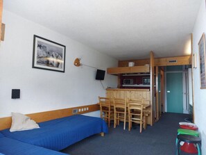A compact room with a single bed, a small dining table with chairs, a kitchenette, and a television mounted on the wall. - 6th floor, view resort, balcony, tv, 40m², Les Arcs (Les Arcs)