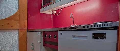 Una cocina compacta equipada con microondas, horno y refrigerador.
