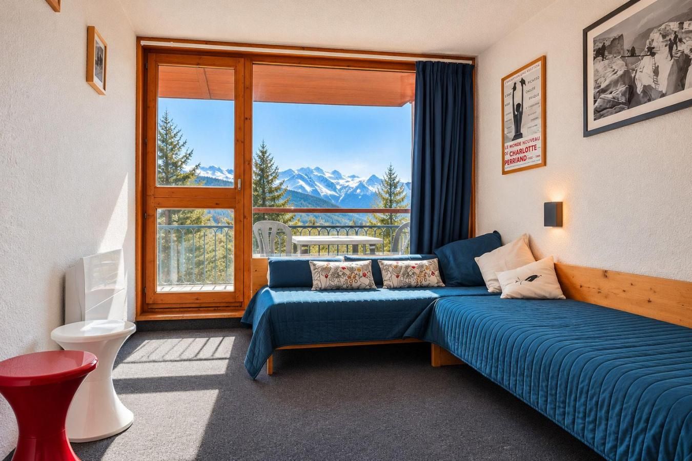 A bedroom with a bed, a chair, a toilet, and a window with a mountain view.