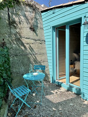 A small, turquoise-painted room with a sliding door leading to a bed. There is a table with chairs outside the room, and a small window with a lamp. - Adorable detached outbuilding with spa area at extra cost (CAGNES-SUR-MER)
